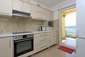 a kitchen with white cabinets and a view of a balcony at Apartments with parking space Dramalj, Crikvenica - 5592 in Dramalj