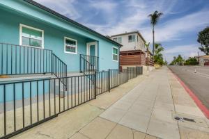 a blue building with a fence next to a street at Hip Walkable Neighborhood Condo in San Diego in San Diego