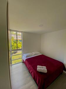 ein Schlafzimmer mit einem Bett mit einer roten Decke und einem Fenster in der Unterkunft Comodo Apartamento Edificio urban in Manizales