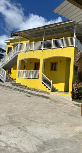 a yellow house with a white balcony on a street at Desired View in Choiseul