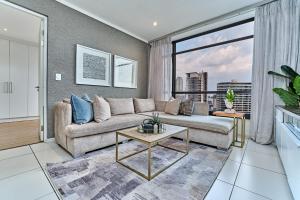 a living room with a couch and a large window at Masingita Towers Hotel, Elegant Sunset Condo in Johannesburg