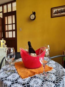 a bottle of wine in a red basket on a table with glasses at Casa de Manolo in Chiclayo