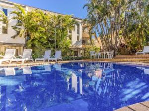 a swimming pool with chairs and a house at Cabarita Beachfront Poolside 28 in Cabarita Beach
