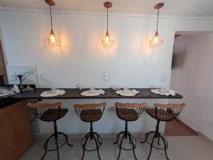 a kitchen with a counter with bar stools and lights at Hospedagem Tiradentes - Centro in Tiradentes