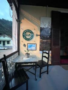 un tavolo e delle sedie su un portico con un orologio sul muro di hostel 148 a Petrópolis