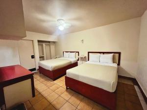 a hotel room with two beds and a table at Hotel León in Tijuana +2 photos