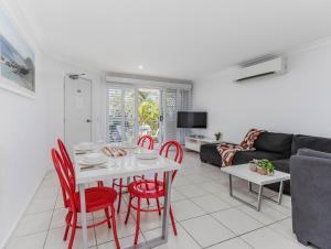 a living room with a white table and red chairs at Cabarita Beachfront Poolside 28 in Cabarita Beach