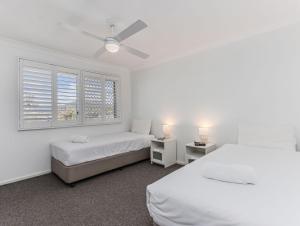 a white bedroom with two beds and a window at Cabarita Beachfront Poolside 28 in Cabarita Beach +14 photos