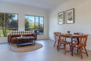 a living room with a couch and a table and chairs at Follow The Sun in Smiths Lake