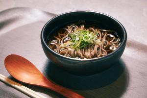 a black bowl of noodles on a plate with a spoon at hotel androoms Shin-Osaka in Osaka