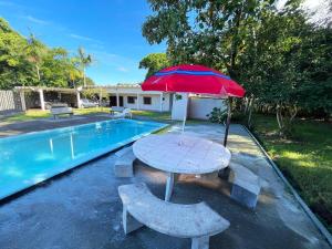 a table with an umbrella next to a pool at Casa Ampla de Praia 2 Piscinas e Ar Condicionado in Matinhos +26 photos