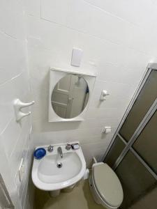 a bathroom with a toilet and a sink and a mirror at Refúgio na Praia 2 Piscinas in Matinhos