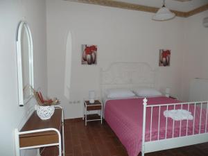 a white bedroom with a pink bed and a table at Villa Eleni in Áfra