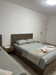 Un dormitorio con dos camas y una pared blanca. en Centrum Apartman & Rooms, en Ulcinj
