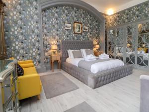 a bedroom with a large bed and a yellow chair at Ismay Billiard Room Apartment - Titanic Interest in Crosby