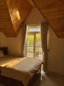 a bedroom with a bed and a large window at Kha Phat Central Dalat with Local Charm in Xuan An