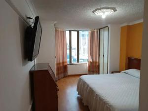 a bedroom with a bed and a flat screen tv at Hotel Sol Internacional in Sogamoso