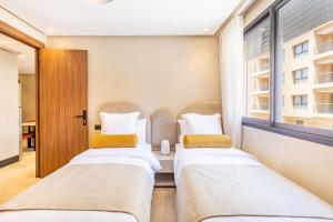 deux lits dans une chambre avec fenêtre dans l'établissement Prestige Apartment in City Center, à Marrakech