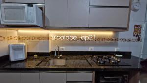 a kitchen counter with a sink and a microwave at Caioba com excelente localização in Matinhos
