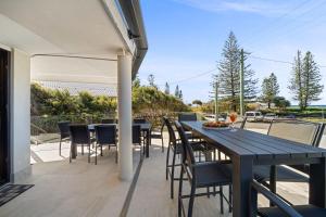 a patio with a table and chairs on a deck at Beachfront with pool ocean views and pet friendly in Buddina +37 photos