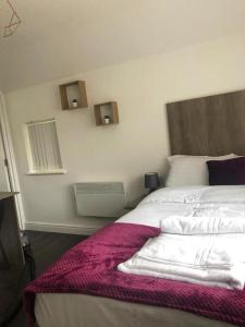 a bedroom with a bed with a purple blanket on it at Train Station - Lancaster Apartments in Leicester