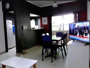 une salle à manger avec une table, des chaises et une télévision dans l'établissement Cómodo y moderno departamento con cochera, a pasos de la principal calle comercial de la ciudad, à La Plata