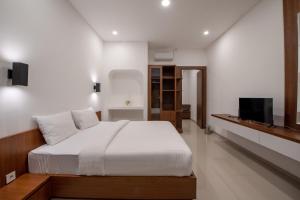 サヌールにあるBaruna Homestay Sanurのベッドと薄型テレビのある寝室
