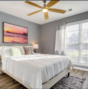 ein Schlafzimmer mit einem weißen Bett und einem Deckenventilator in der Unterkunft Stylish Retreat in Lawrenceville in Lawrenceville