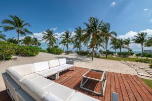 a white couch sitting on a wooden deck next to a beach at 3BR Beachfront Luxury Apt w/First Class Amenities in Cancún