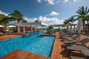 a large swimming pool with chairs and umbrellas at 3BR Beachfront Luxury Apt w/First Class Amenities in Cancún