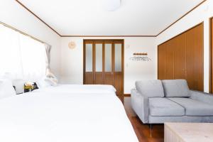 ein Schlafzimmer mit einem Bett und einer Couch in der Unterkunft エアポートサイドOmura in Omura