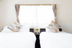 zwei Betten in einem Zimmer mit Fenster in der Unterkunft エアポートサイドOmura in Omura