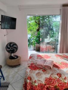 a bedroom with a bed and a tv and a window at Suíte com Entrada Independente in Florianópolis