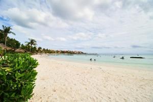 a beach with people swimming in the water at BeachFront Appt w/Amazing Pool in Puerto Aventuras in Puerto Aventuras