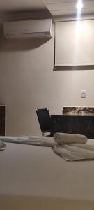 CambéにあるMotel Monte Carloのベッド1台と椅子1脚が備わる客室です。
