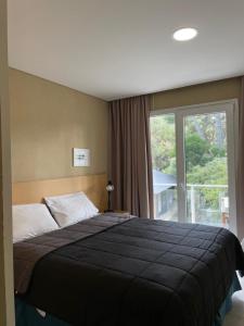 a bedroom with a bed and a large window at Nexo Playa Depto 6 in Valeria del Mar
