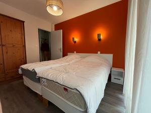 a bed in a bedroom with an orange wall at Spacieux appartement refait à neuf avec balcon et garage, proche centre-ville - FR-1-498-108 in Évian-les-Bains
