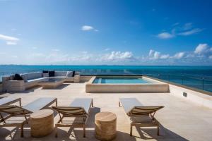 a patio with chairs and a swimming pool on a building at 5BR Luxury Beachfront Penthouse w/ Private Pool in Isla Mujeres