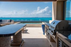 a patio with a grill and a view of the ocean at 5BR Luxury Beachfront Penthouse w/ Private Pool in Isla Mujeres +58 photos