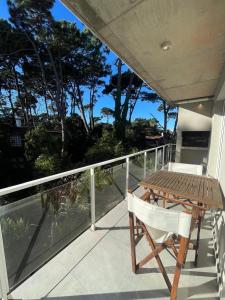 a wooden table and a chair on a balcony at Nexo Playa Depto 6 in Valeria del Mar