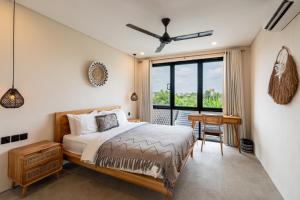 a bedroom with a bed and a table and a window at Hati Villa by Betterplace in Canggu