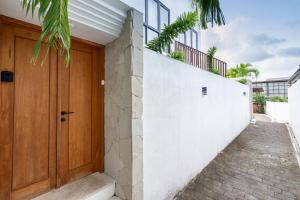 a wooden door on a white wall next to a stairs at Hati Villa by Betterplace in Canggu +54 photos