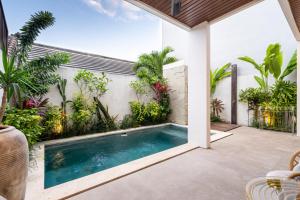 an indoor swimming pool in a backyard with plants at Hati Villa by Betterplace in Canggu
