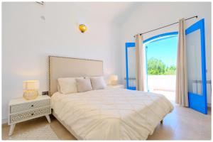 a white bedroom with a bed and a large window at Dar zeytouna in Hammamet +14 photos