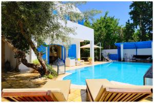 a swimming pool with chairs and a building at Dar zeytouna in Hammamet