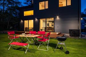 a table with chairs and a grill in front of a house at Flagpole Villa Hakuba in Hakuba