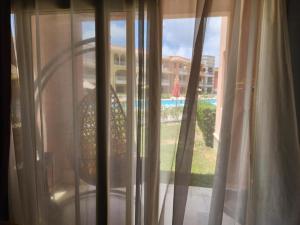 a window with white curtains and a view of a pool at بورتو مطروح ألهاني families only in Marsa Matruh