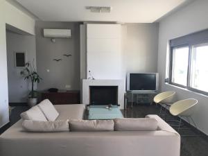 a living room with a white couch and a tv at Akti Villa in Kissamos
