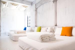 Habitación blanca con 4 camas y almohadas coloridas. en Oats B&B en Hengchun Old Town