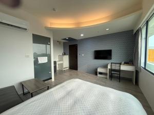 a bedroom with a bed and a desk and a television at 勤天行旅-嘉義站前 in Chiayi City